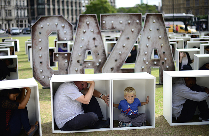 Volunteers sit in wooden boxes at Parliament Square, to represent living conditions in Gaza, during a protest in London